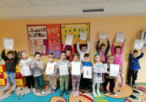 Zdjęcie grupowe dzieci z planszami edukacyjnymi dotyczącymi zjawisk pogodowych