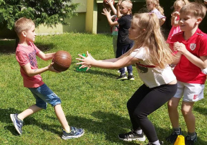 Wyścig rzędów - chłopiec przekazujący dziewczynce piłke lekarską