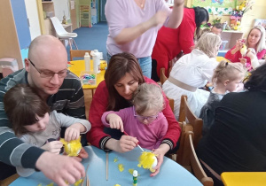 Dziewczynki wyklejają kury z rodzicami.