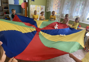 Zabawy średniaków chustą animacyjną i piłeczkami.