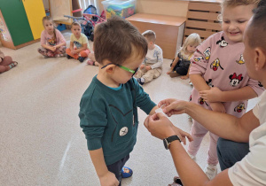 Doktor przyklajejący dziecku plaster.