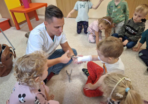 Dzieci i doktor rozcinający dziecku gips.