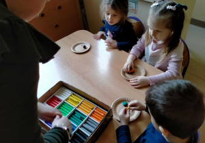 Dzieci lepią pączki i faworki z plasteliny.