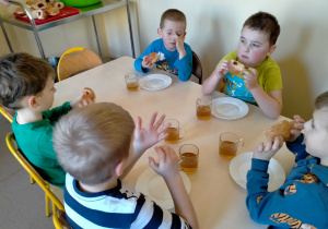 Dzieci jedzą pączki.