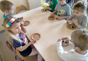 Dzieci lepią paczki i faworki z plasteliny.