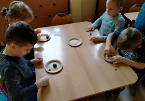 Dzieci lepią paczki i faworki z plasteliny.