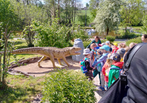 Pani przewodnik omawia dinozaura.