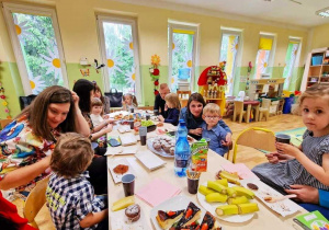Dzieci z rodzicami, częstują się słodkim poczęstunkiem.
