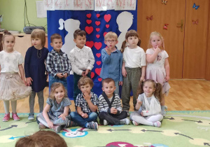 Dzieci pozują do zdjęcia na tle dekoracji z okazji "Dnia Mamy i Taty".