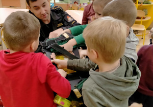 Dzieci sprawdzają ciężar butli z tlenem wykorzystywanej podczas akcji pożarniczej.