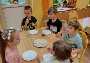 Dzieci jedzą owoce.