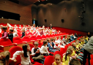 Dzieci siedzą na teatralnej widowni.