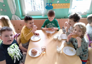 Dzieci jedzą pyszne pączki.