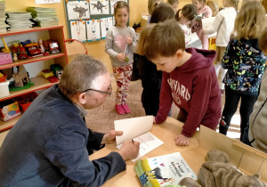 Pisarz wypisuje w swojej książce, dedykację dla Gucia.