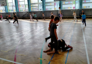 Dziewczynka przechodzi pod nogami chłopca, tworzącego tunel.