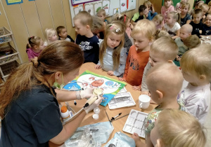 Pani stomatolog prezentuje dzieciom sprzęt dentystyczny.