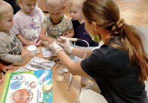 Pani stomatolog prezentuje dzieciom sprzęt dentystyczny.