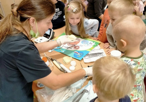 Pani stomatolog prezentuje dzieciom sprzęt dentystyczny.