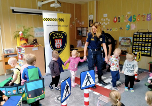 Dzieci odgrywają role pieszego i kierowcy w miasteczku ruchu drogowego.