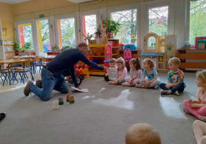 Pan instruktor pokazuje dzieciom zdjęcia naczyń ceramicznych.